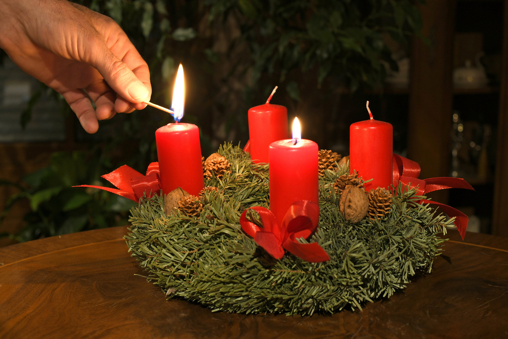 Eine Kerze am Adventkranz wird angezündet